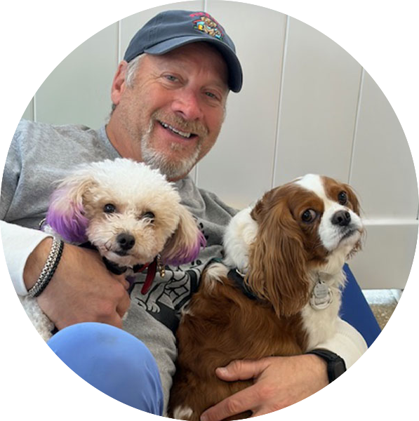 Joel hugging a couple dogs at the Pup E Club USA during a daycare visit